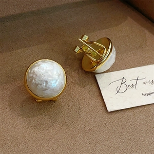Detailed view of vintage gold clip-on earrings with textured white pearl-like centers