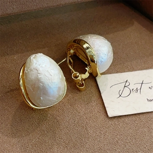 Detail of baroque pearl earrings with vintage gold base on a jewelry tray