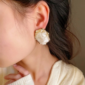 Close-up of a large irregular geometric earring with marble resin and gold metal edge