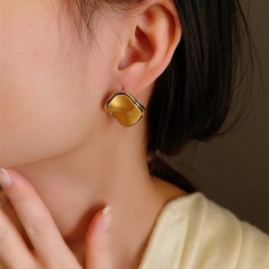 Close-up of two-tone brushed metal wave earrings with silver and gold finish
