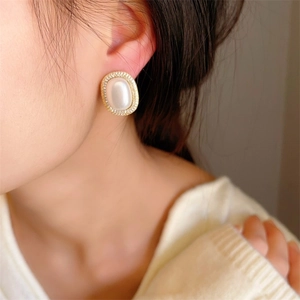 Detail of oval pearl earring with pavé rhinestones on a golden alloy frame