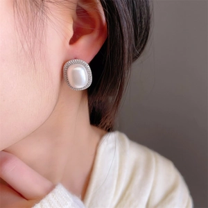 French retro oval pearl earrings with sparkling crystal halo on model's ear