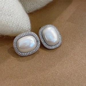 Vintage oval pearl earrings with micro-pave crystals on silver base over warm felt background