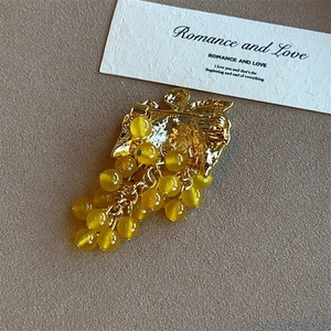 Close-up of vintage grape brooch with golden alloy leaves and amber crystal beads