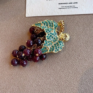 Detailed close-up of grape cluster earring with purple beads and teal rhinestones