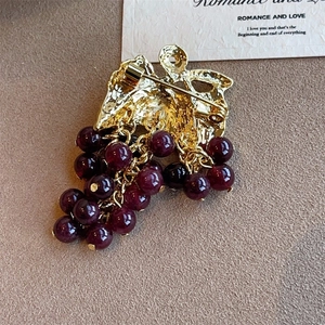 Detail of the golden metal base and pin fastener on a grape-shaped beaded brooch