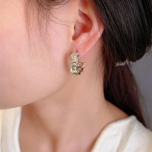 Luxurious C-shaped gold hoop earrings with square-cut crystal zircon on model's ear