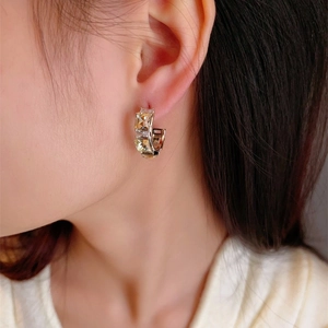 Macro view of C-shape gold earrings inlaid with square champagne cubic zirconia