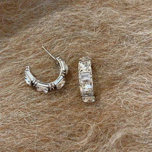 Silver C-shaped hoop earrings with rectangular cubic zirconia on a brown fur surface