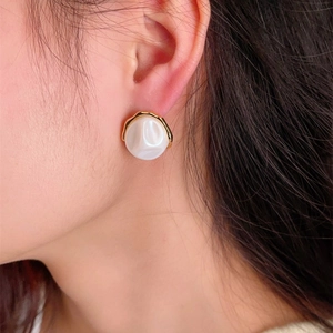 Close-up of minimalist gold-edged baroque pearl earrings worn for a luxury look