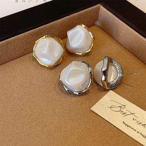 Detailed view of gold and silver irregular baroque pearl earrings on brown velvet padding