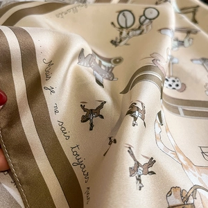 Détail du foulard en soie montrant des animaux de manège et un fini satiné doré