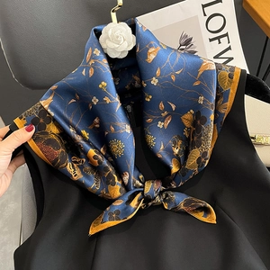 Navy blue silk scarf with floral bird print and white camellia brooch on black vest