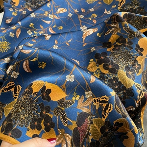 Luxurious navy silk scarf with gold floral bird print and elegant draped satin texture
