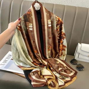 Écharpe en soie artistique avec imprimé abstrait et broche camélia sur canapé
