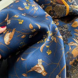Detailed view of silk scarf fabric showing smooth texture and bird floral print