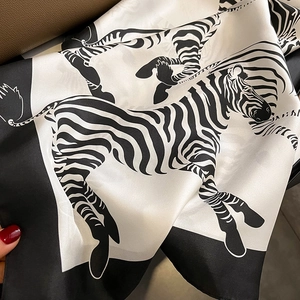 Elegant zebra print silk square scarf tied on a brown leather handbag handle