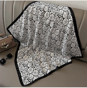 Detail of elegant black and white floral silk scarf displayed with fashion accessories