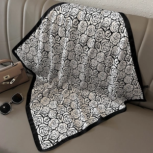 Detail of square silk scarf with black and white rose print on a leather surface