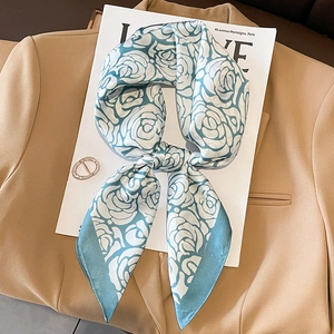 Elegant floral silk scarf in lake blue and white displayed on a professional blazer