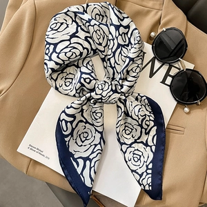 Elegant navy and cream silk scarf with rose floral print styled on a brown blazer
