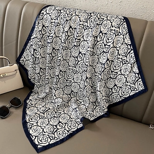 Detail of silk scarf with black and white rose print and dark blue border on a sofa