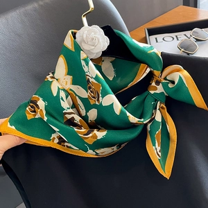 Foulard en soie verte à motif rose et décor de camélia sur robe noire