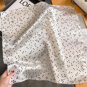 Carré en soie blanc cassé à pois noirs élégant présenté avec des accessoires de luxe