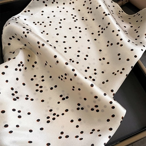 Gros plan d'un foulard en soie à pois noirs avec un drapé fluide et une texture douce