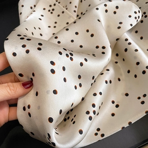 Vue détaillée d'un foulard en soie léger montrant la texture fluide et le motif à pois