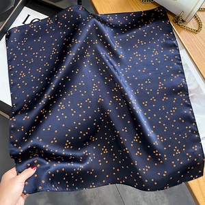 Carré de soie bleu marine à pois orange présenté avec un sac à main et un magazine