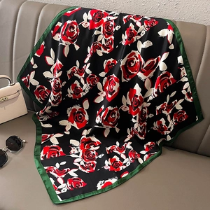 Élégant foulard en soie noir aux motifs de roses rouges posé sur une chaise