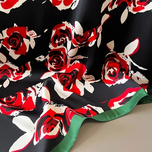 Détail d'un foulard en soie montrant l'imprimé rose rouge et les bords roulottés main