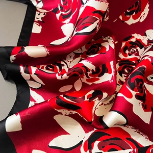 Détails d'un foulard en soie rouge avec de grands motifs de roses et bordure noire
