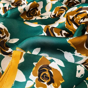 Vue détaillée du motif de roses vintage sur foulard en soie vert émeraude et bord jaune