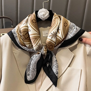 Silk-style square scarf with geometric pattern tied elegantly on a beige blazer collar