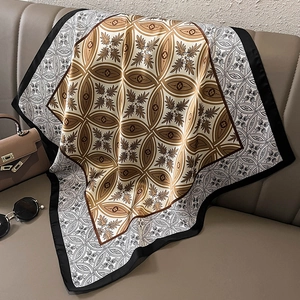 Detail of elegant silk square scarf with geometric patterns draped on a leather sofa