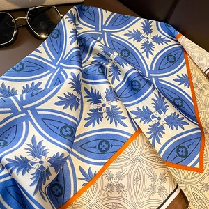 Detail of blue and white silk scarf with geometric patterns and orange edge
