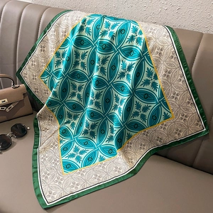 Detail of luxury emerald green silk square scarf with vintage geometric prints on sofa