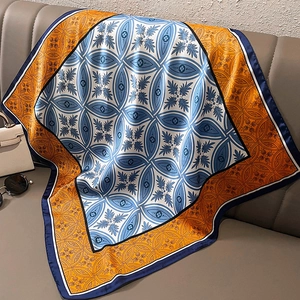Detailed view of luxury satin square scarf with baroque patterns draped on sofa