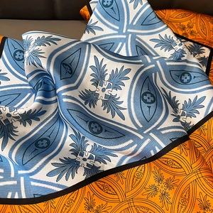 Detailed close-up showing silky satin fabric texture and geometric print of the square scarf