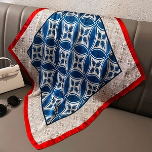 Detail of red and blue silk square scarf with geometric patterns on a leather sofa