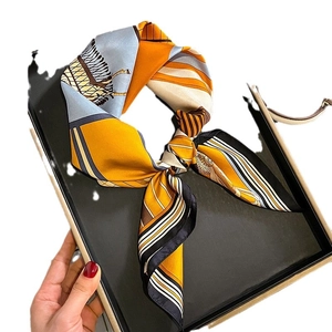 Elegant silk scarf with vibrant orange and blue geometric patterns on a black display tray