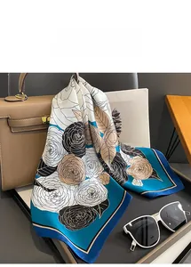 Detail of silk scarf with camellia pattern draped on a leather bag with high-end texture