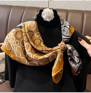 Detail of silk-texture square scarf tied over a black turtleneck sweater