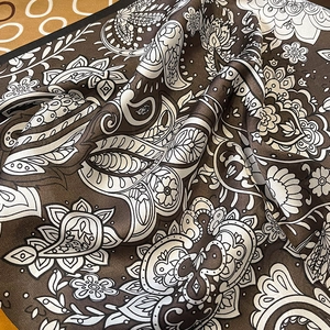 Detailed view of silk-textured paisley square scarf with glossy brown satin folds