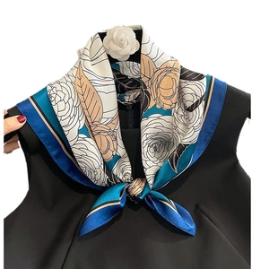 Fashion silk scarf with camellia floral print tied on a black dress collar