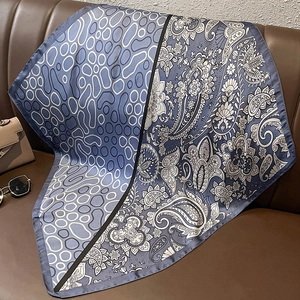 Close-up of paisley print silk scarf displayed on leather with fashion accessories