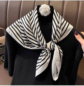 Close-up of black and white diagonal striped silk scarf tied in a stylish neck knot
