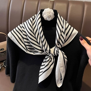 Elegant black and white striped silk scarf with camellia flower on a black sweater